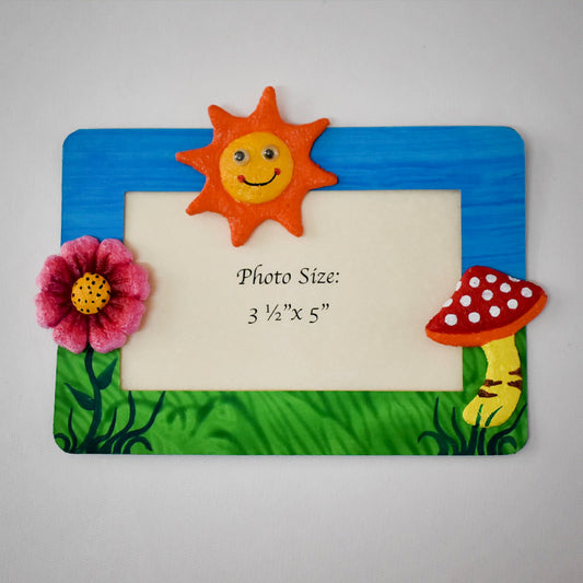 A rectangular Magnetic Photo frame exquisitely  handmade with paper pulp  designs - Pink Flower, Mushroom with white dots on red & a smiling Sun in Orange and Yellow.